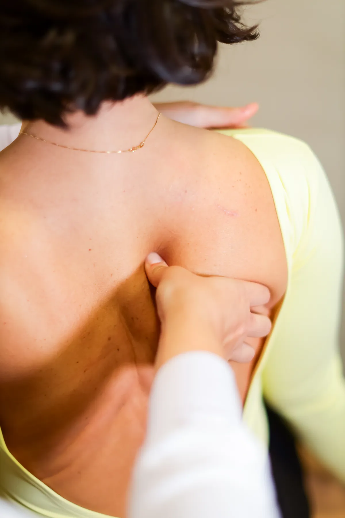 Fisioterapeuta da Fisions avaliando a musculatura das costas de uma paciente durante o atendimento