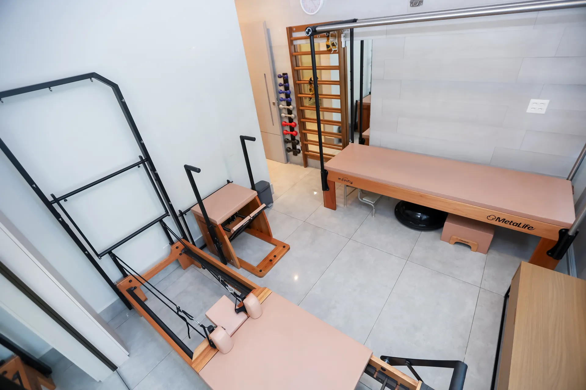 Estúdio de pilates e reabilitação da Fisions em Brasília, com equipamentos de madeira em tons rosé